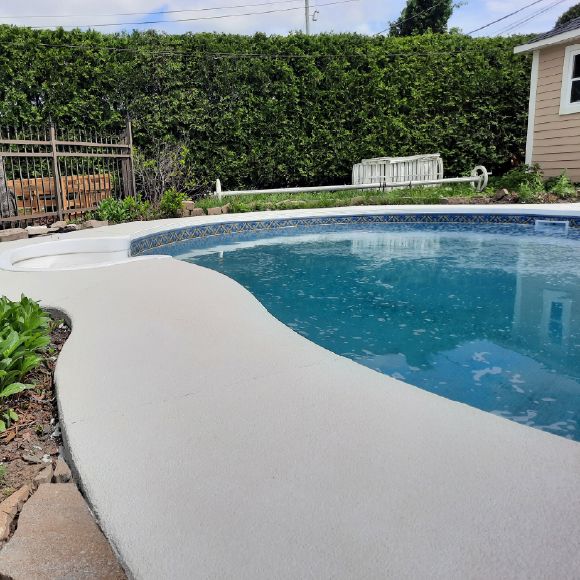 Application de crépi acrylique sur un contour de piscine en béton.