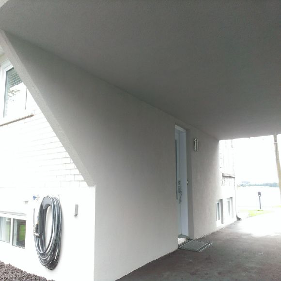 Application professionnelle de crépi acrylique sur un plafond extérieur en béton.