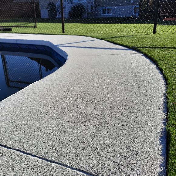 Réparation d’un contour de piscine en béton avec crépi acrylique durable.